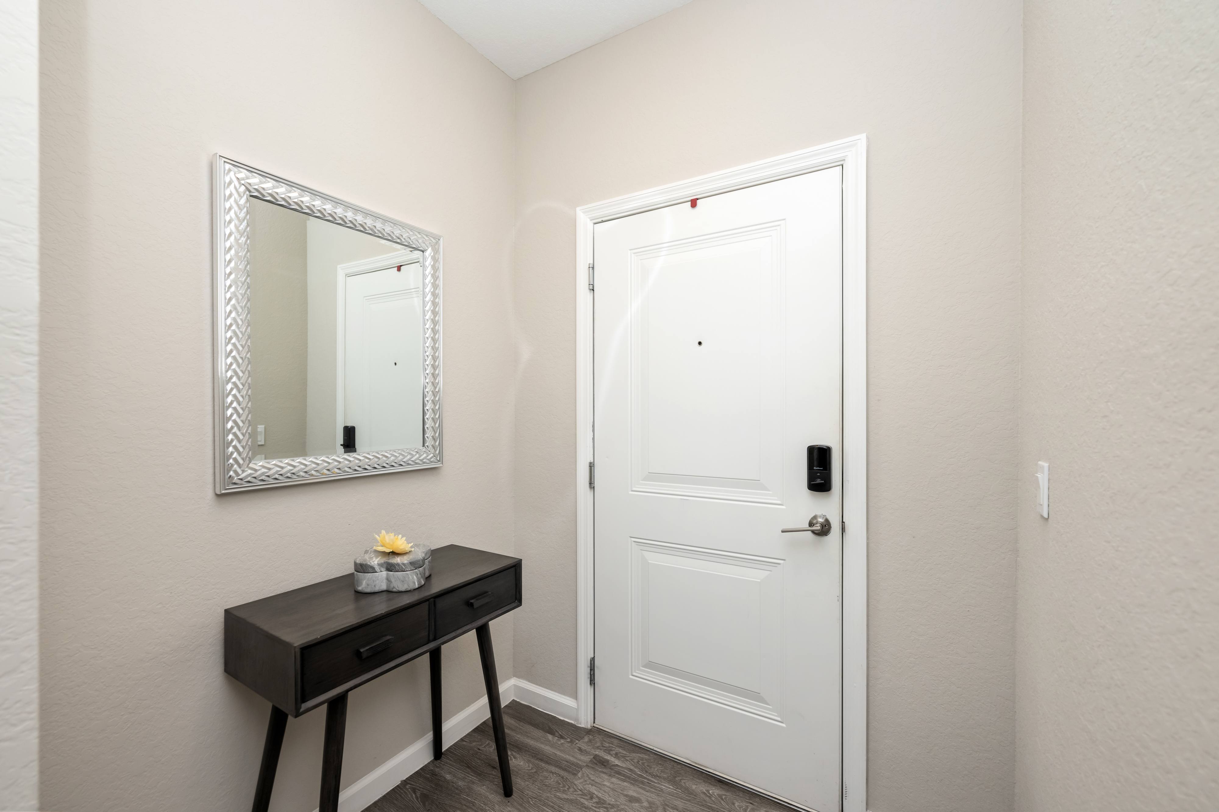 A white door is in a room with a black desk and a mirror.
